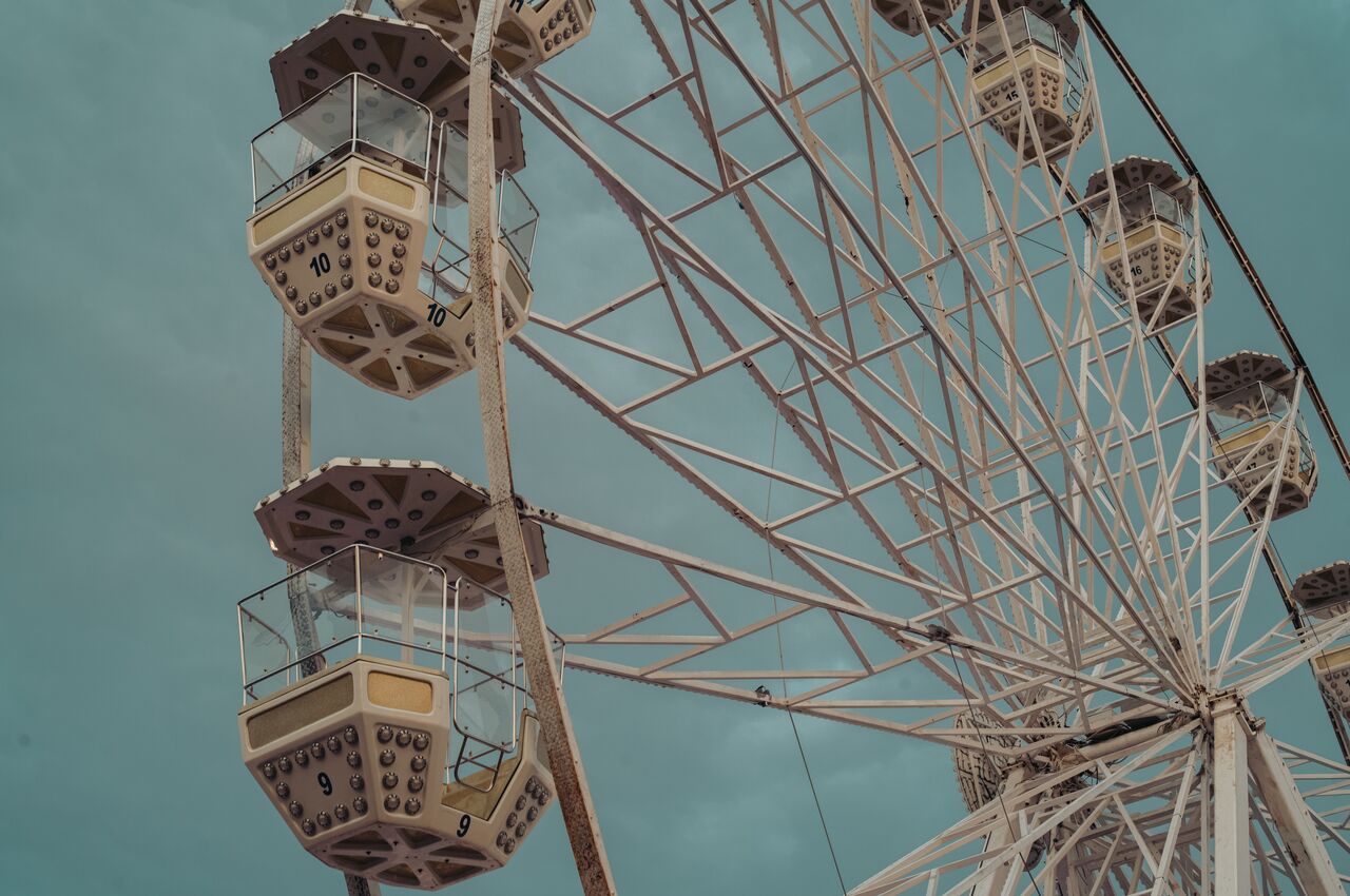 Numbered gondolas of a Ferris wheel against a muted teal sky, with the metal spoke framework visible.