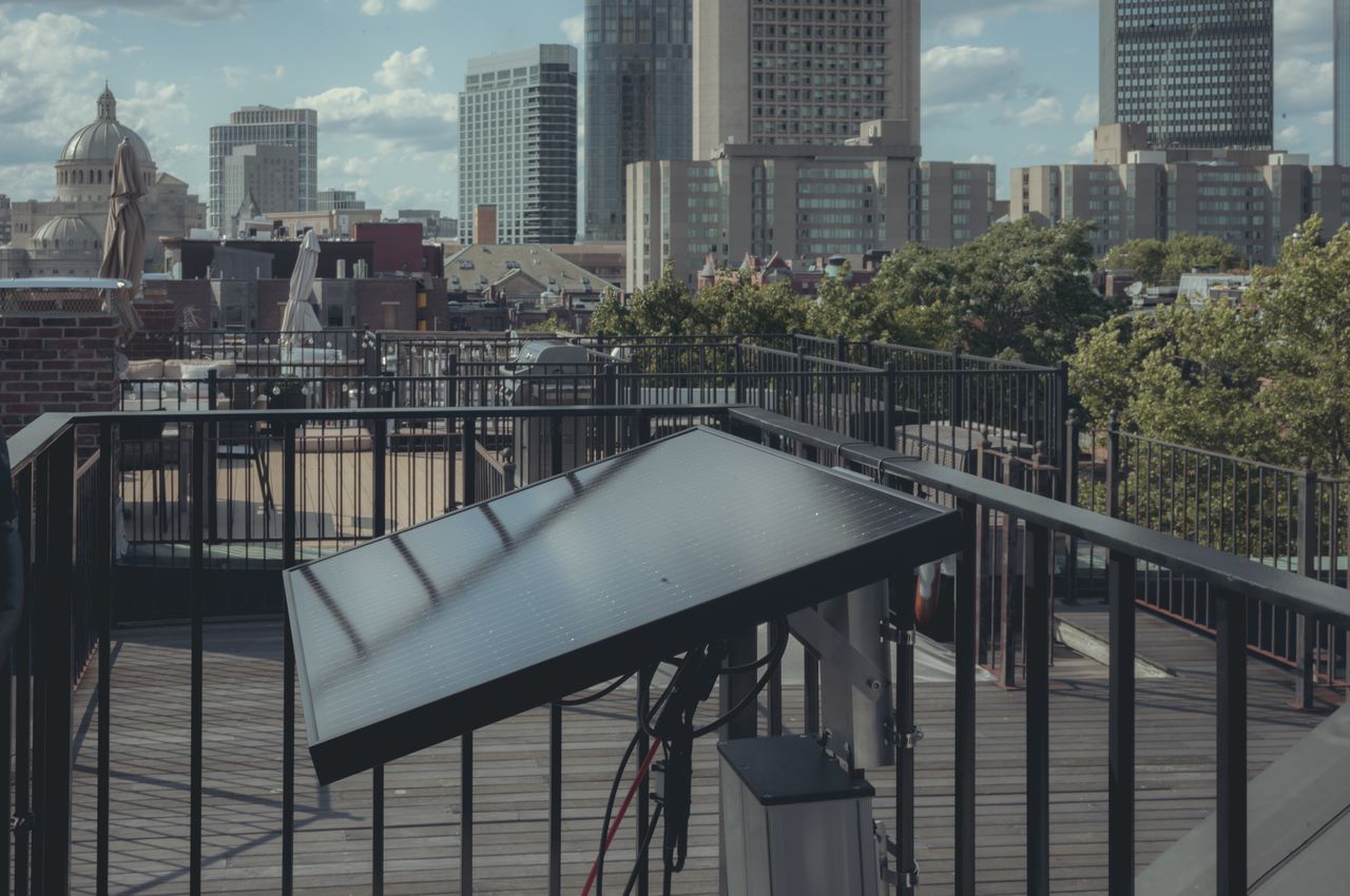 A solar panel and battery mounted securely on a roof deck railing.