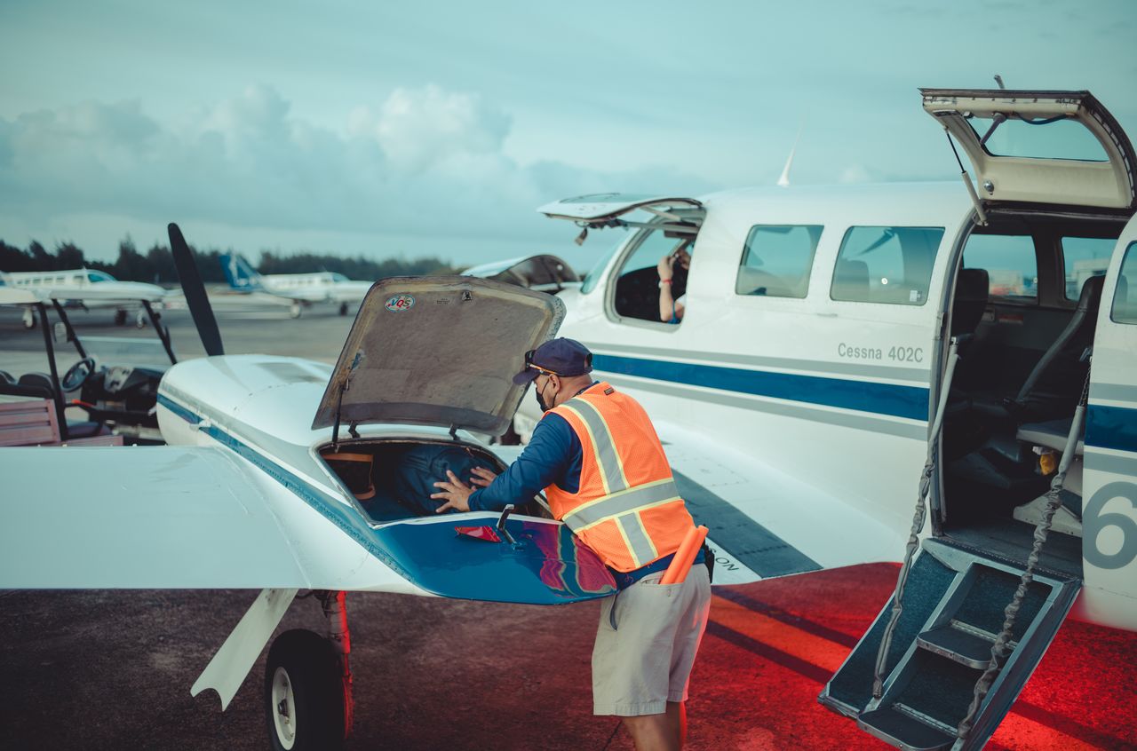 An airline worker stuffing luggage in the wing of a small plane
