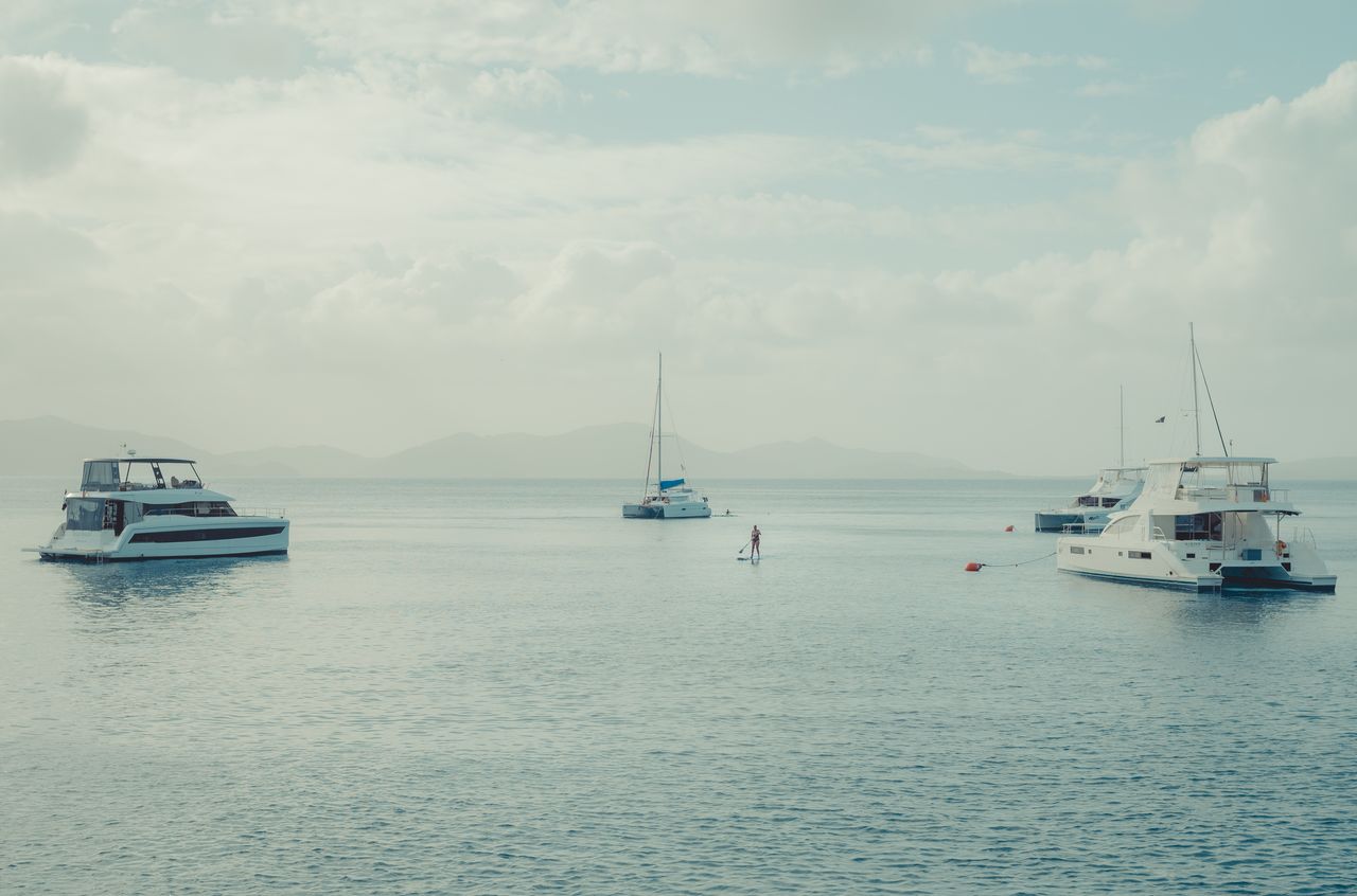 Paddle board A woman standing on a paddle board, surrounded by boats on mooring balls