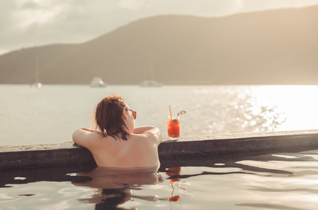 Vanessa watching the sunset from an infinity pool while having a cocktail