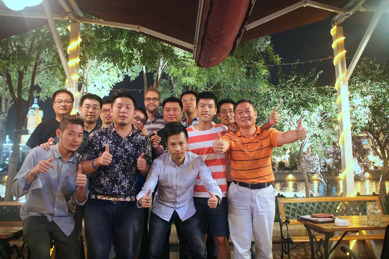 A group of people at a Drupal meetup in Tianjin, posing together and giving thumbs-up gestures.