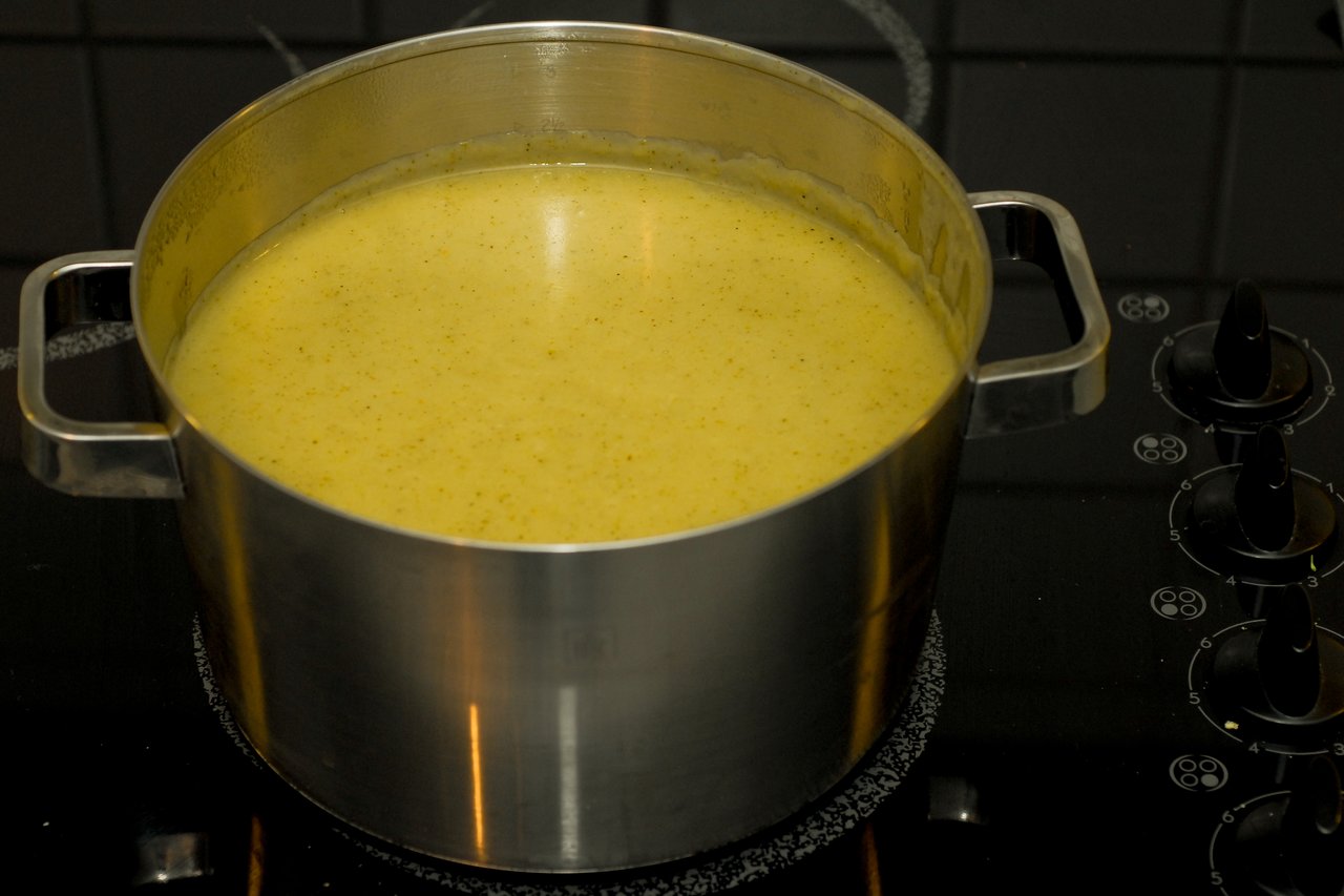 A large pot of broccoli cream soup cooking on a stovetop.