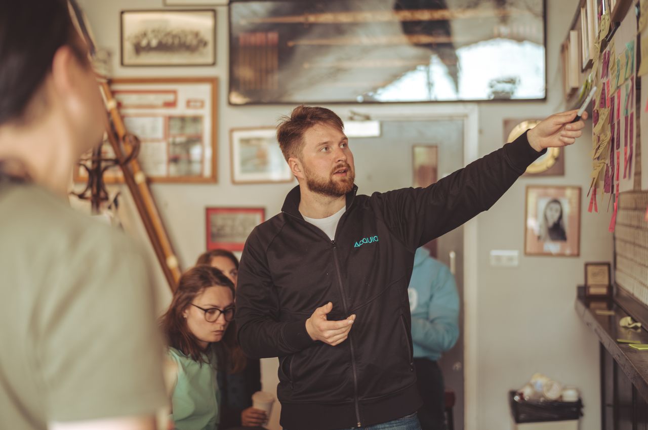 A man is leading a brainstorming session, pointing to sticky notes as he guides the discussion.