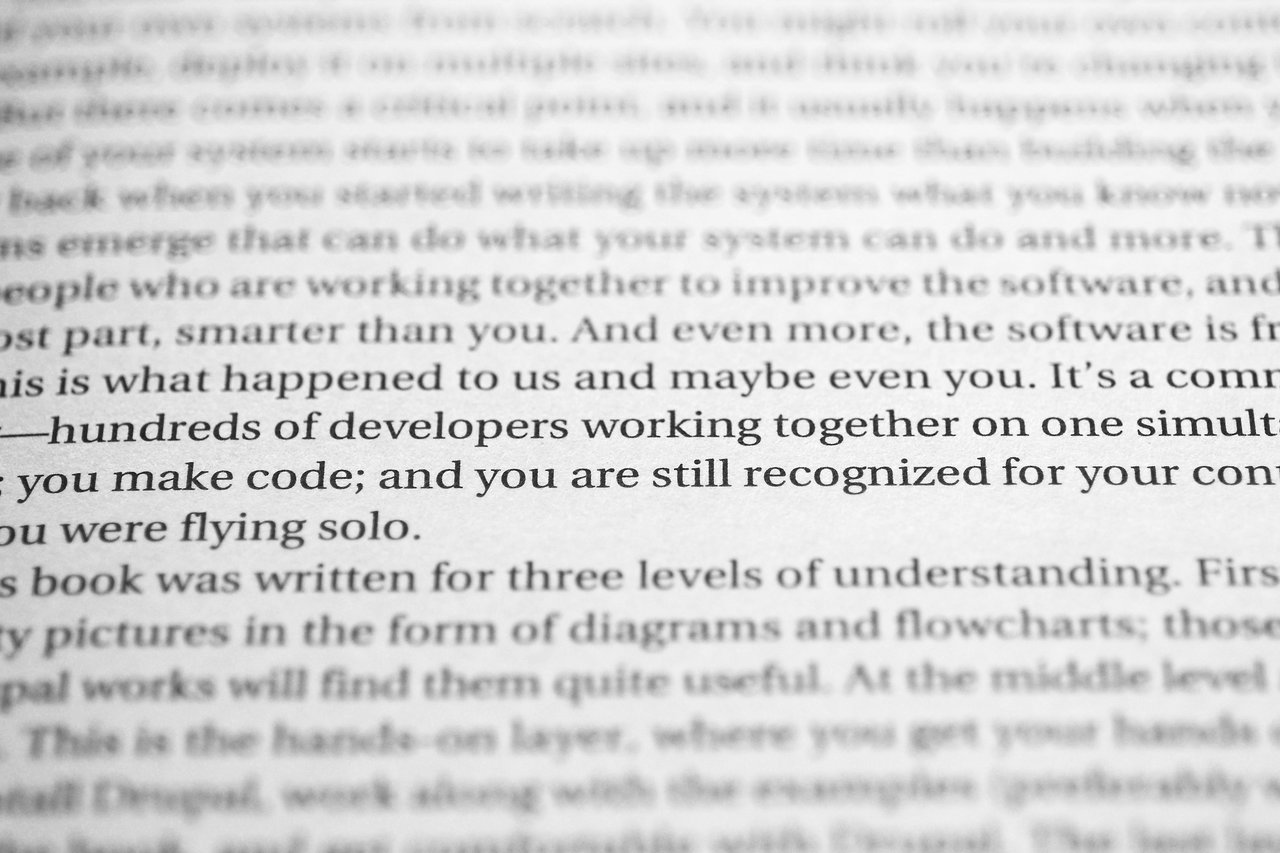 Close-up of a book page highlighting developers collaborating on code and receiving recognition for their contributions.