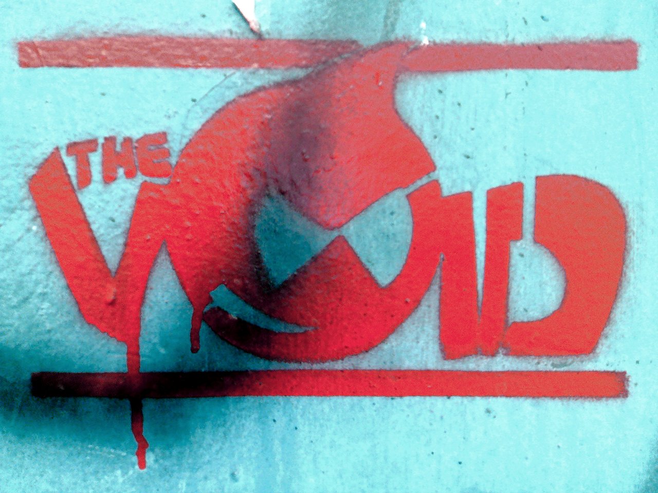 Red graffiti of an angry Druplicon face with the words &quot;THE VOID&quot; on a blue wall.