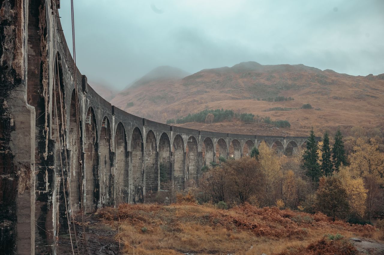 A curved bridge with stone arches connecting two valleys.