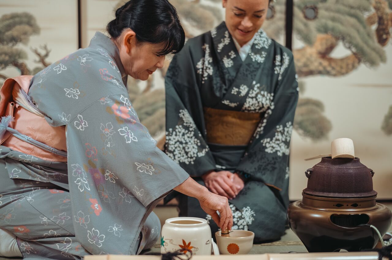 A woman in a kimono prepares matcha tea while another woman watches during a traditional Japanese tea ceremony in Tokyo.