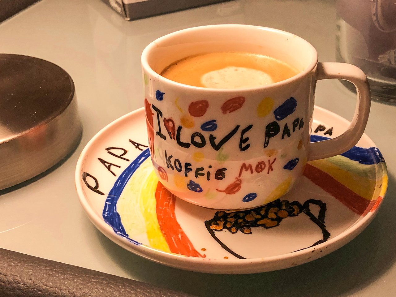 A colorful coffee mug with "I Love Papa" written on it, placed on a matching saucer with decorations.