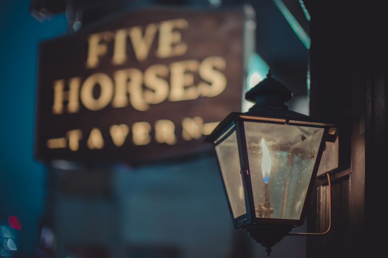 A gas light on the wall of a tavern called 'Five horses'.
