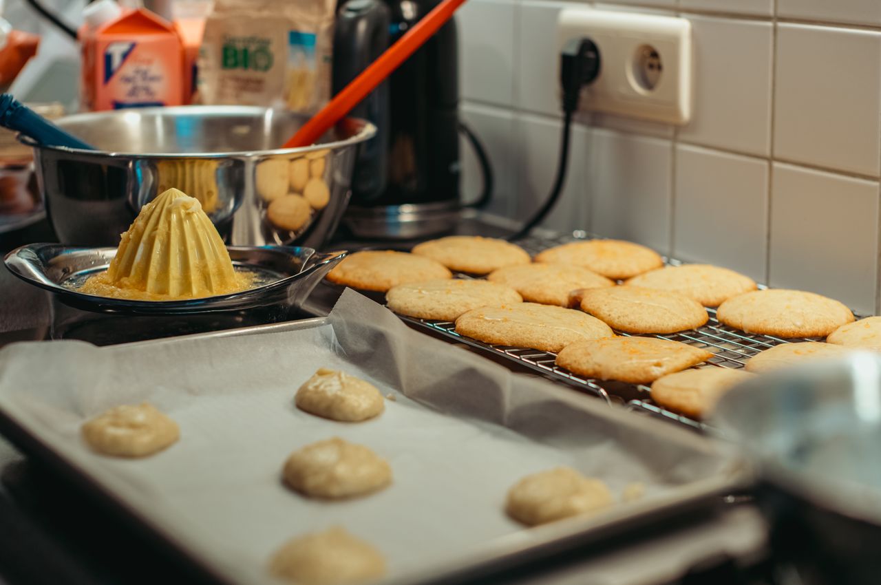 A baking sheet holds freshly baked orange cookies.