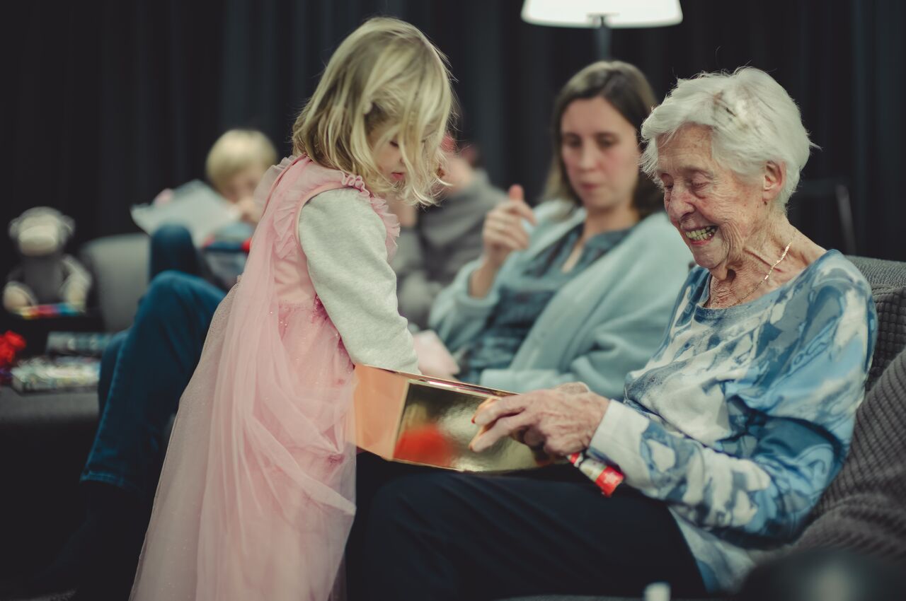 My Oma unwrapping a Christmas gift with the help of her great-granddaughter.