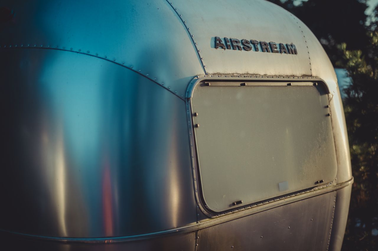 A close-up of the aluminum exterior of an Airstream basking in a warm sunset glow.