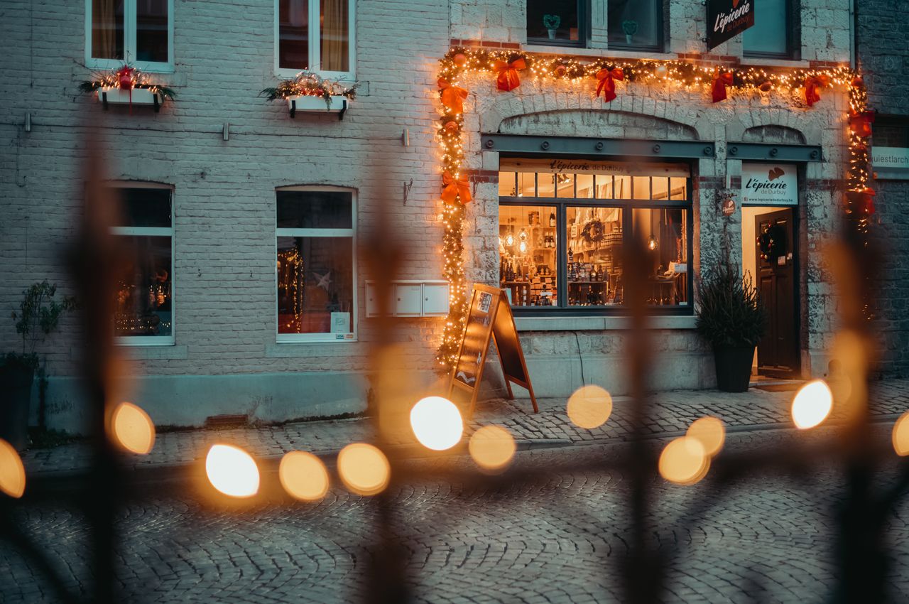 The store front of a small shop, decorated with Christmas lights.