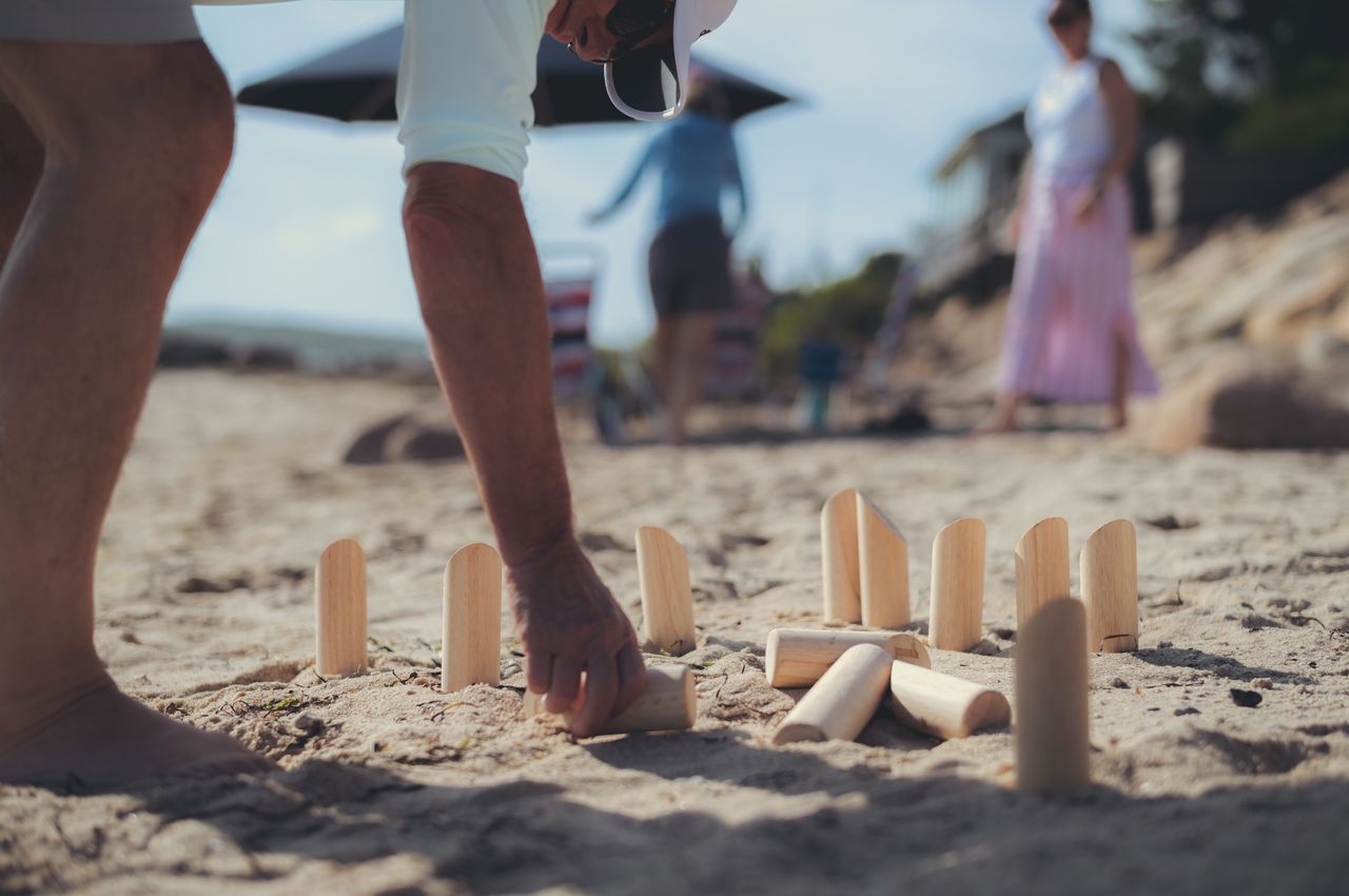 A person on the beach setting up wooden pins for a game.
