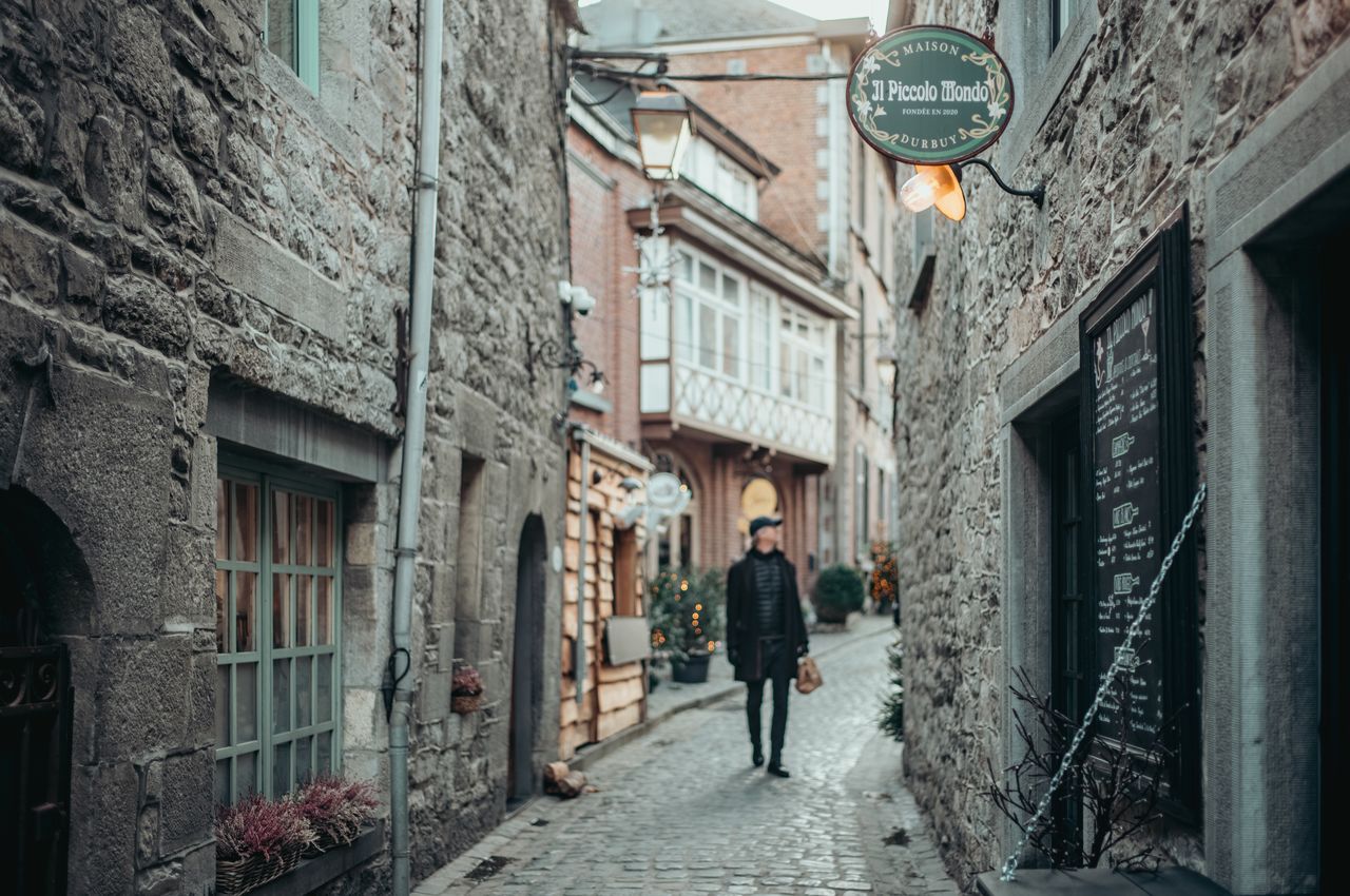 A person walking on a cobblestone street surrounded by old buildings.