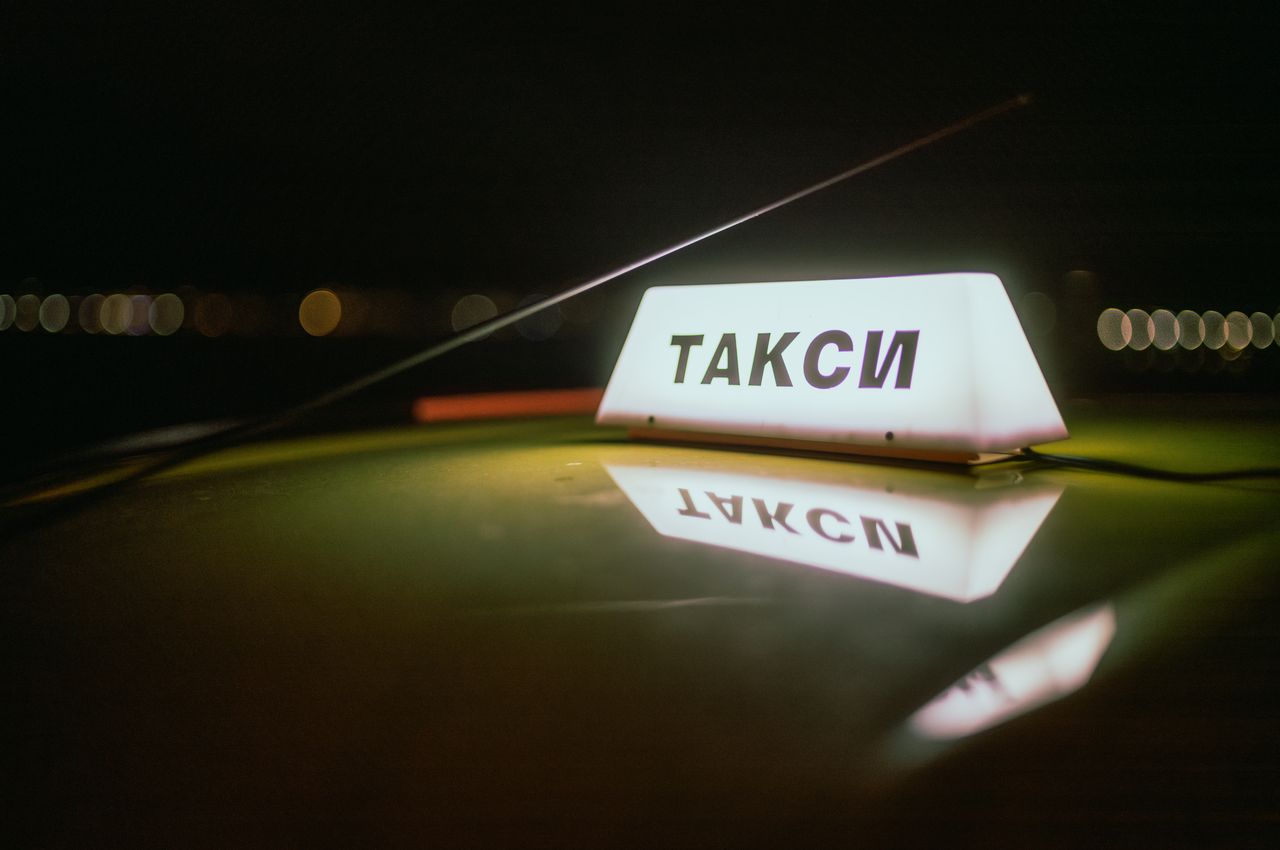 An illuminated taxi sign on the roof of a car.