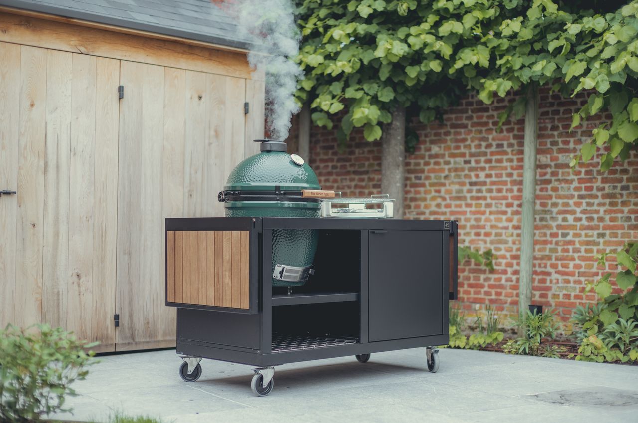 Big Green Egg grill smoking on a patio.