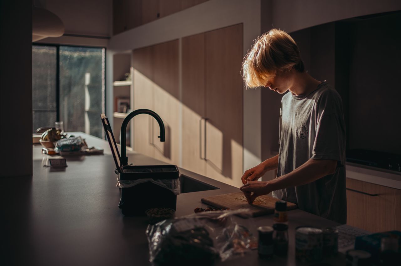 A person mincing garlic at a kitchen island as the sun sets.