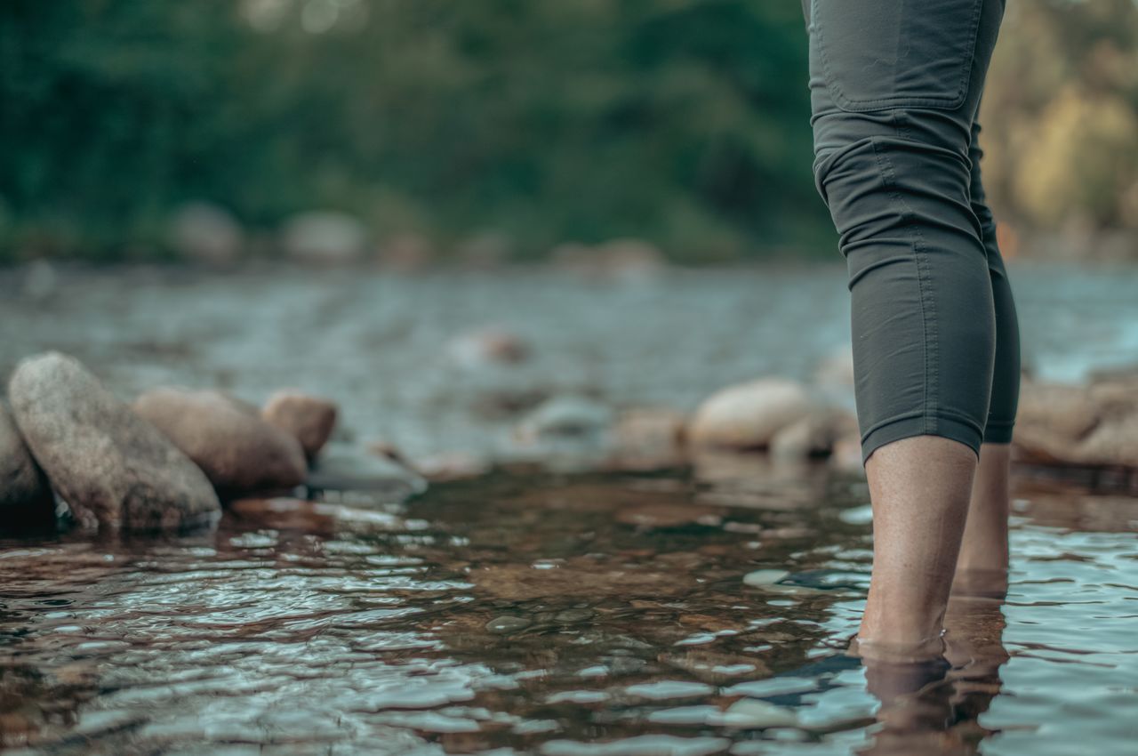 A woman standing in the shallow water of a creek.