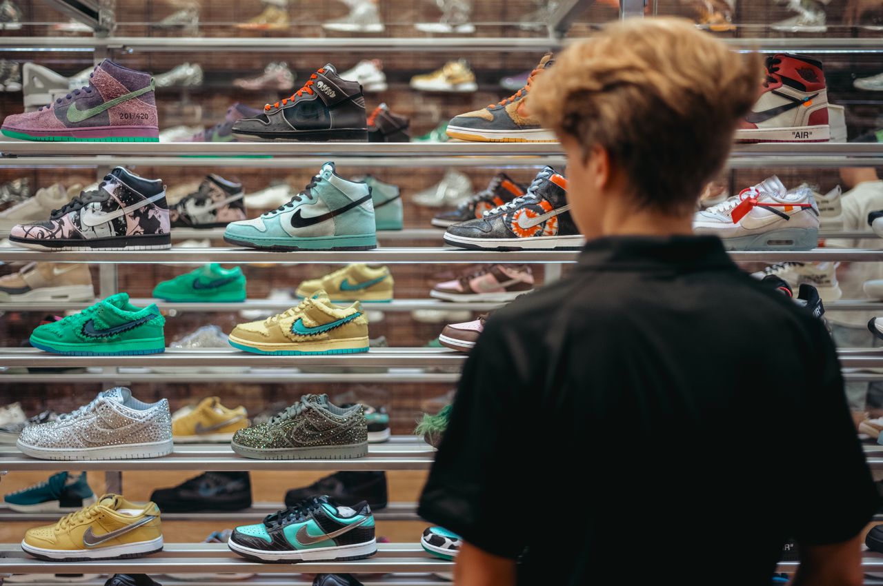 A young man stands in front of sneakers in a glass case.