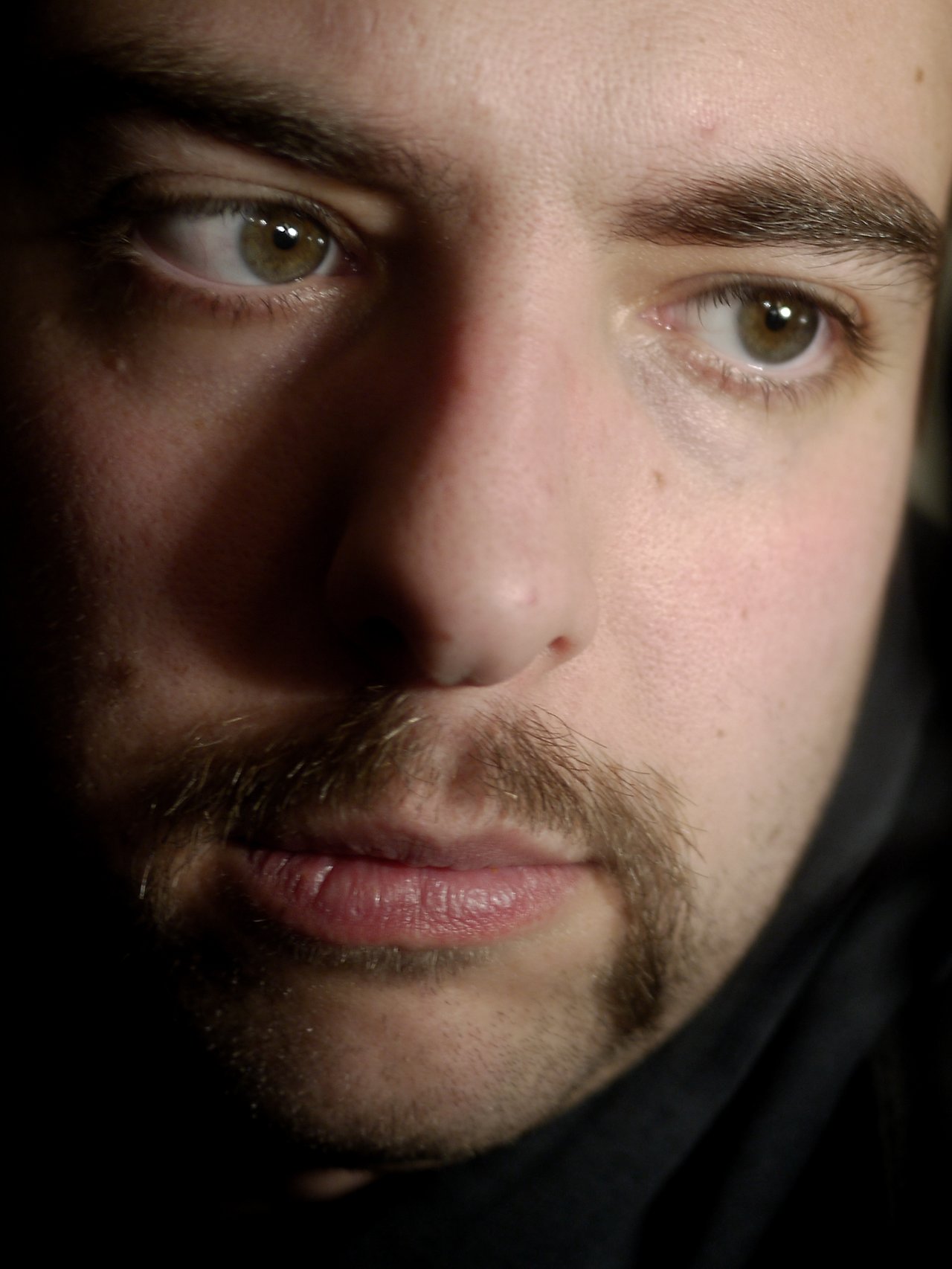 Close-up of a man's face with a mustache, looking to the side.