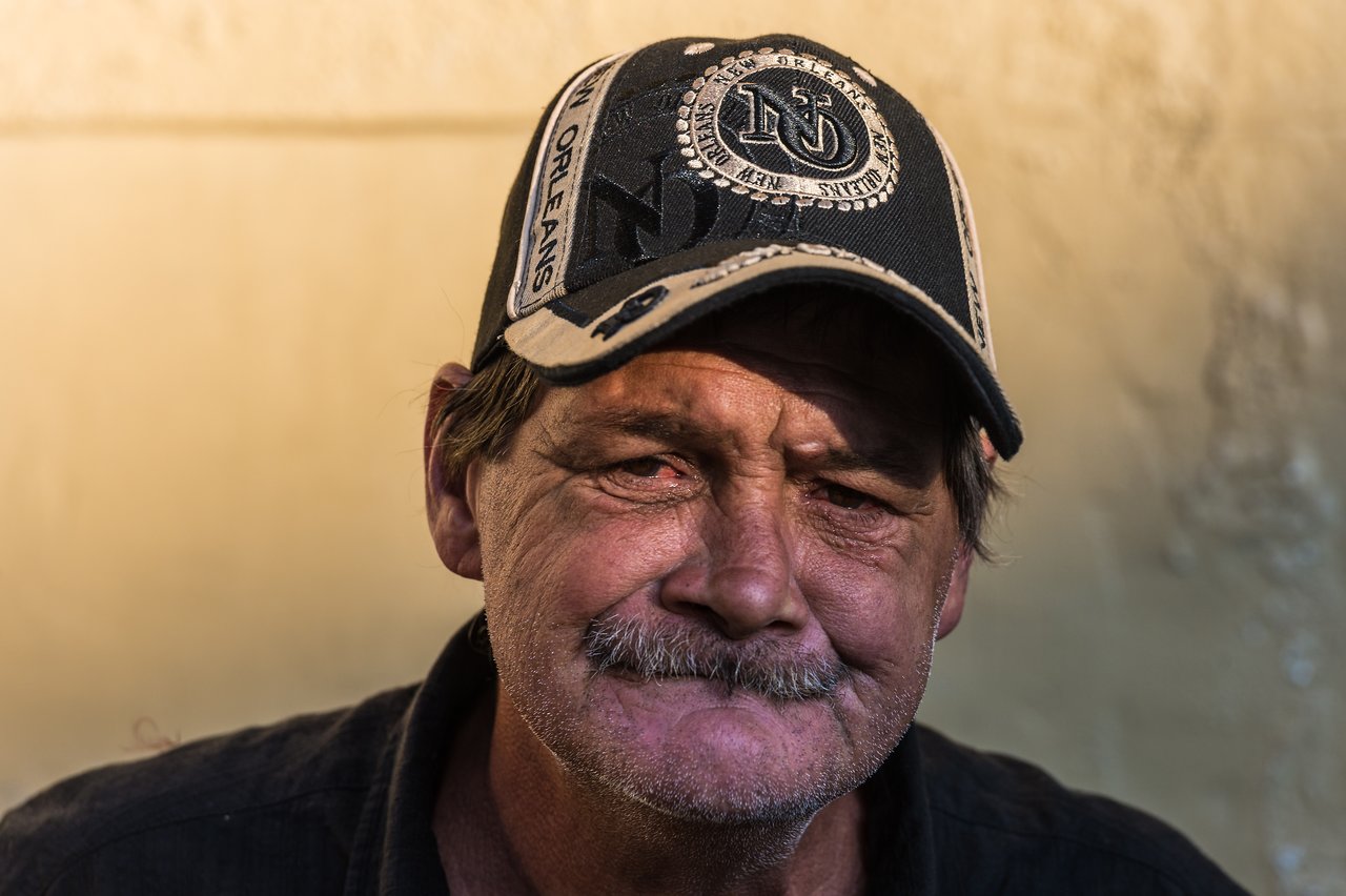 A man wearing a New Orleans cap looks directly at the camera with a neutral expression.