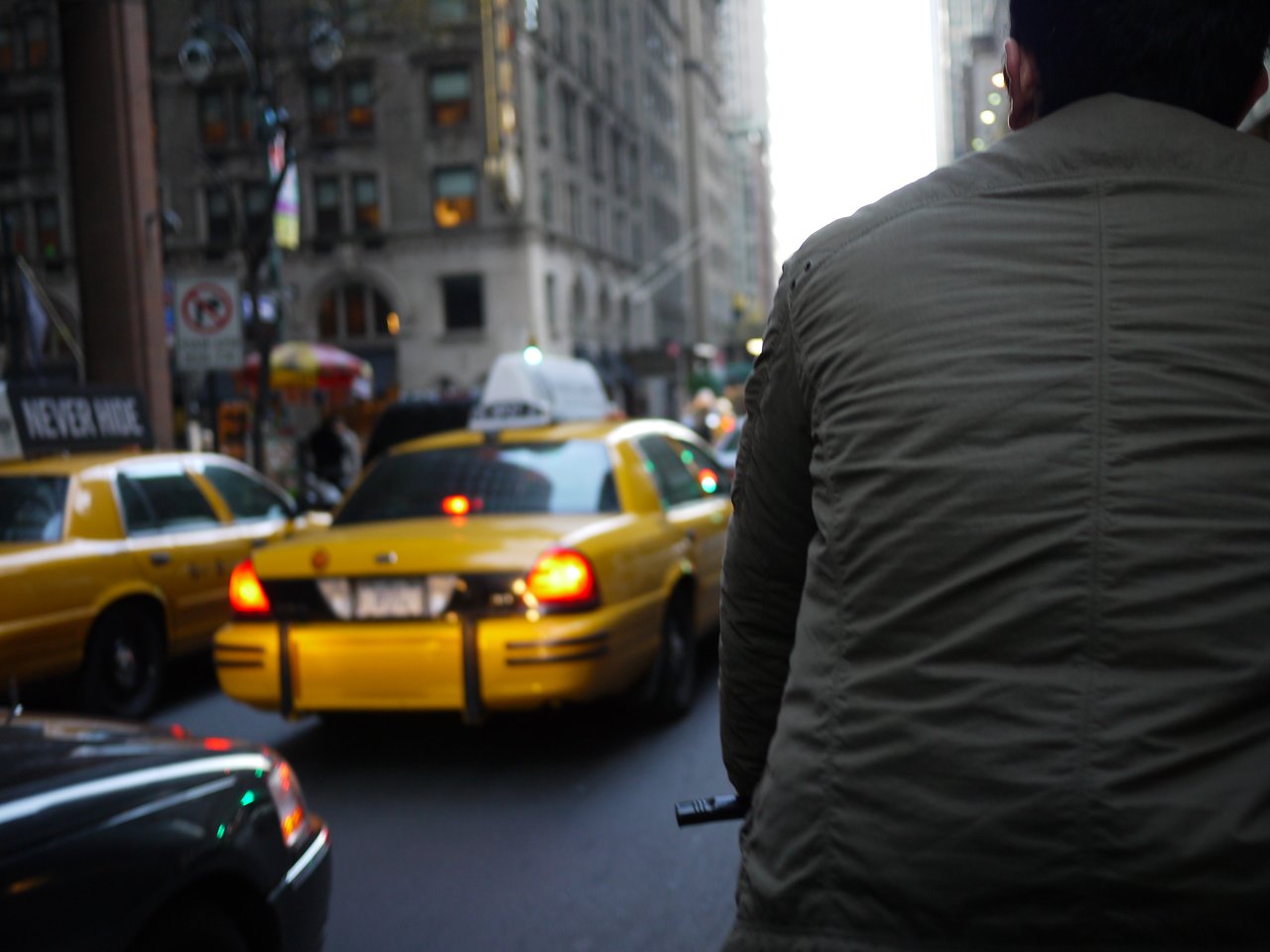 A pedicab ride through Manhattan traffic, with the driver's back on the right and yellow taxis ahead.