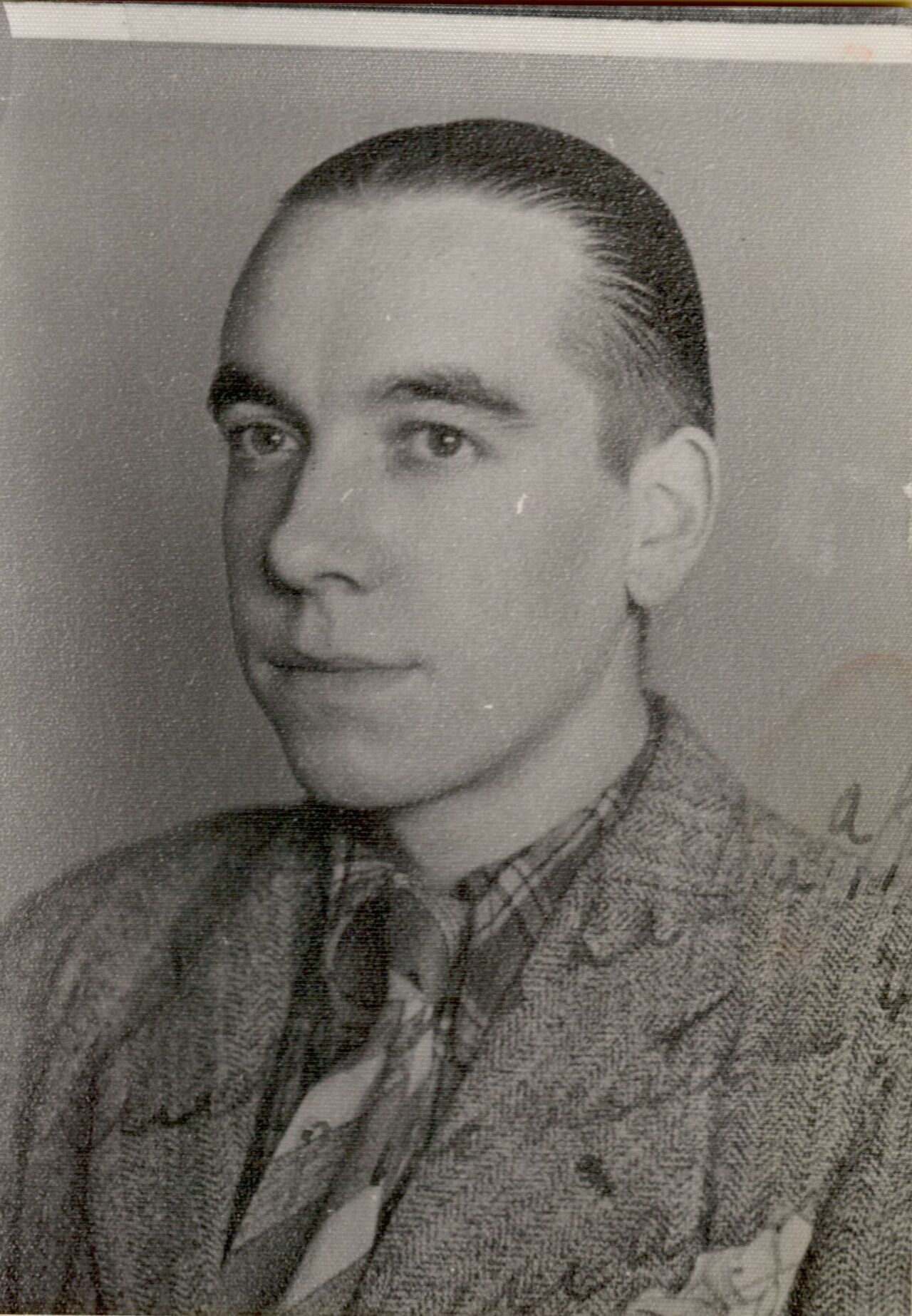 Black-and-white portrait of a man in a suit and tie, looking slightly to the side with a neutral expression.