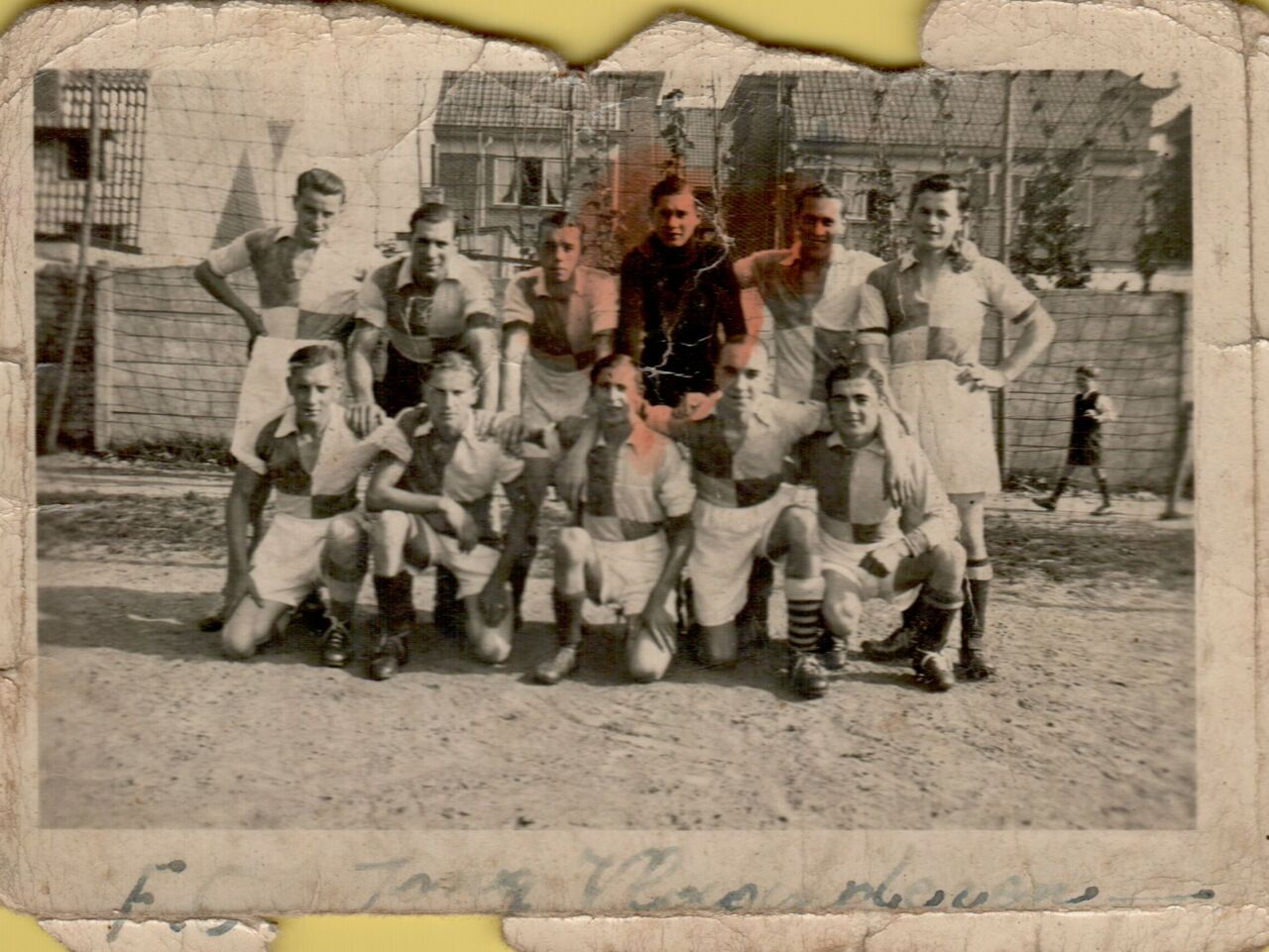 A vintage photo of a soccer team posing together on a dirt field, wearing matching uniforms with checkered patterns.