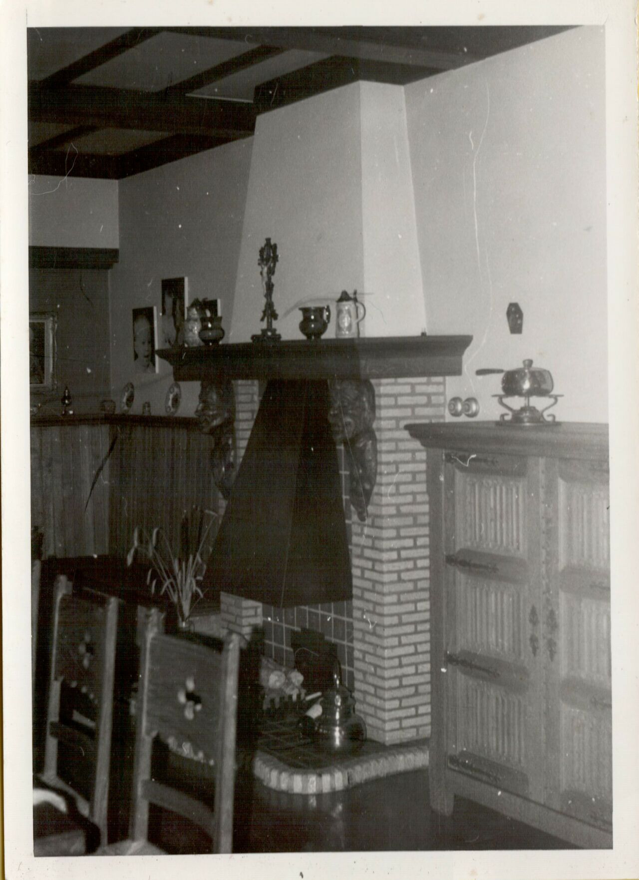 A cozy living room with a brick fireplace, wooden furniture, and decorative items on the mantel and shelves.