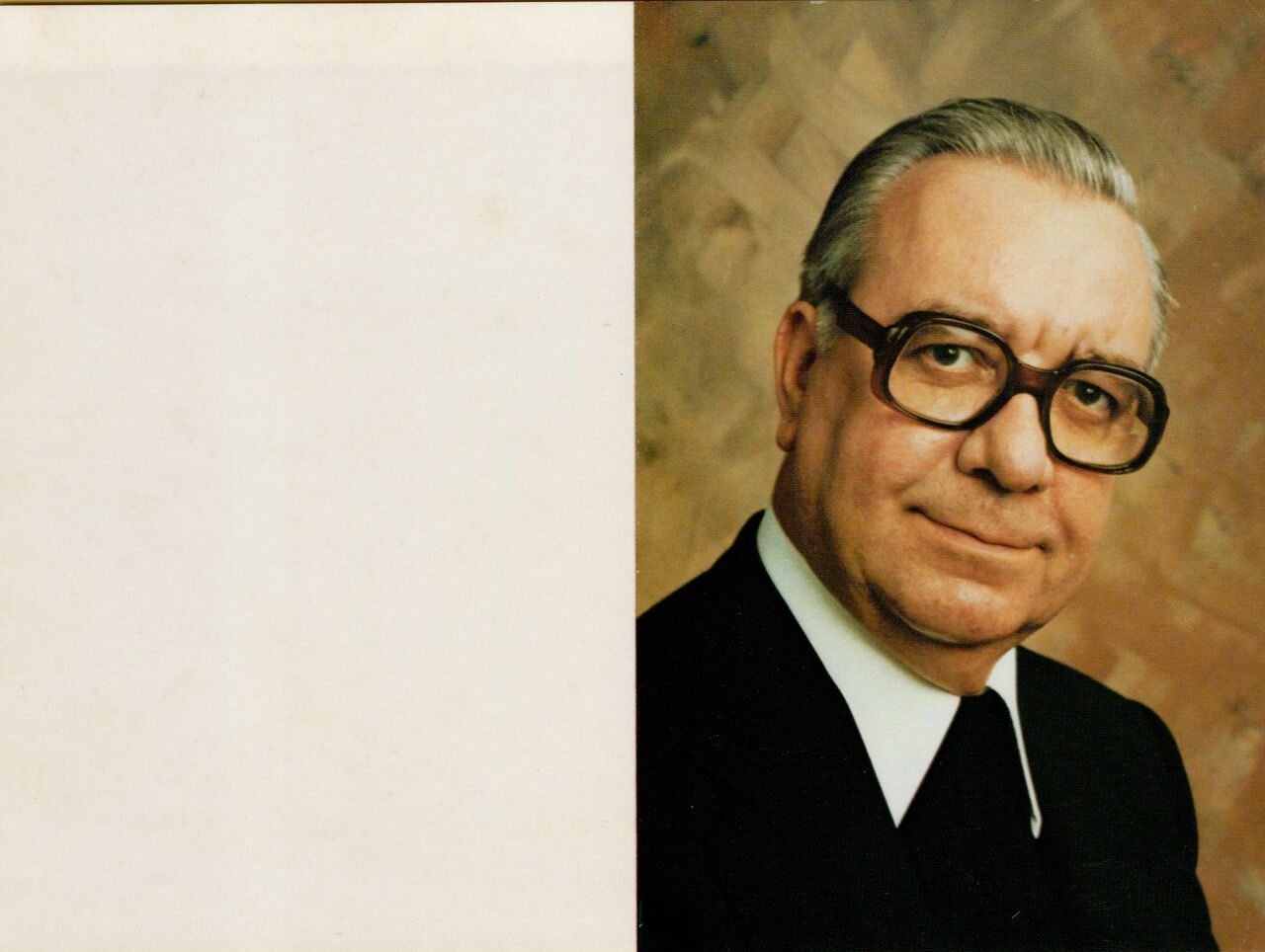 A memorial card featuring a portrait of an older man wearing glasses and a suit, with a blank left page.