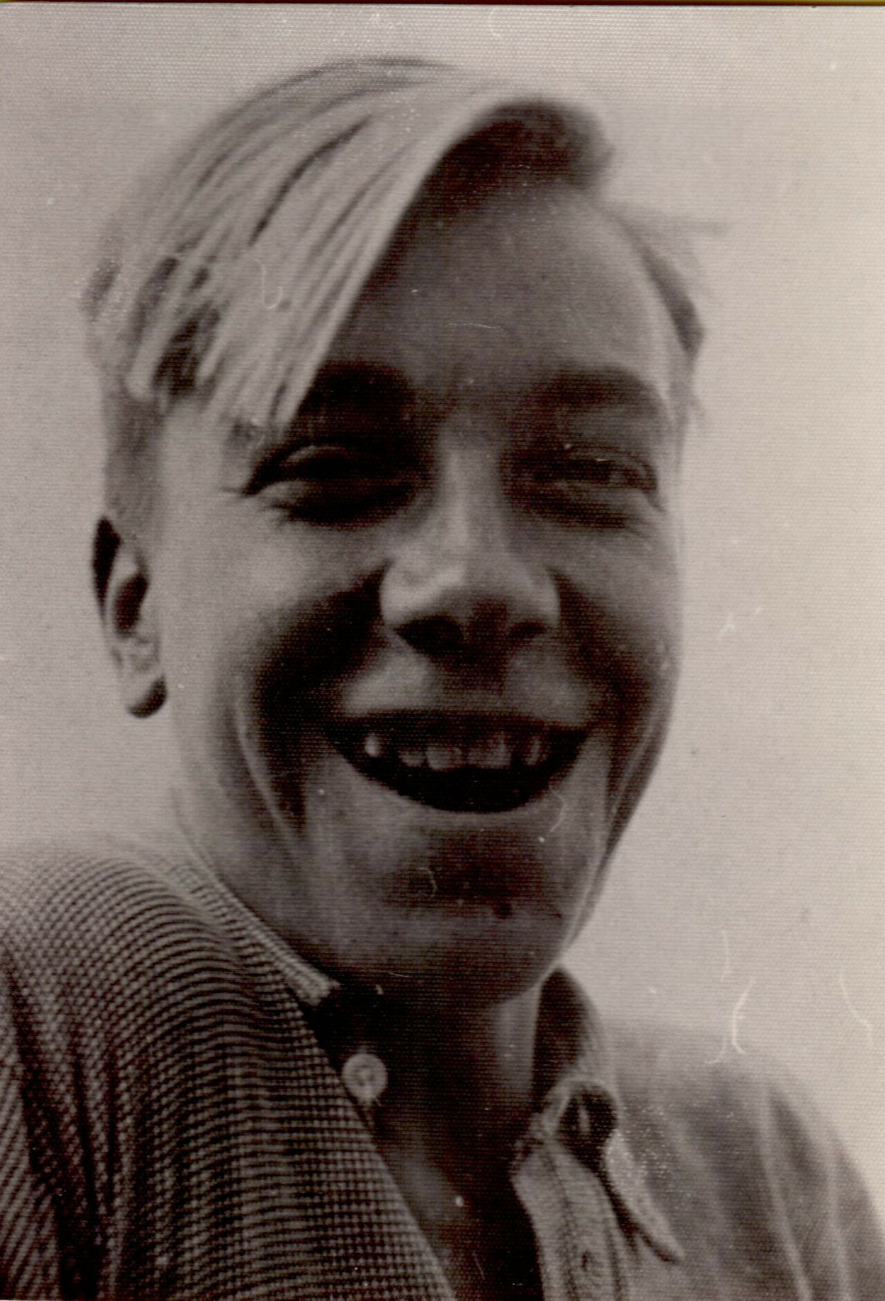 A young man with light hair smiles broadly at the camera, wearing a button-up shirt.