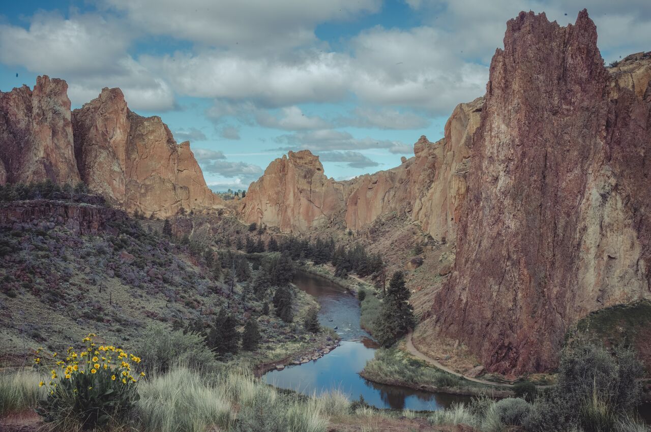 Smith Rock State Park Tall rock cliffs surround a winding river and hiking trail at Smith Rock State Park in Oregon.
