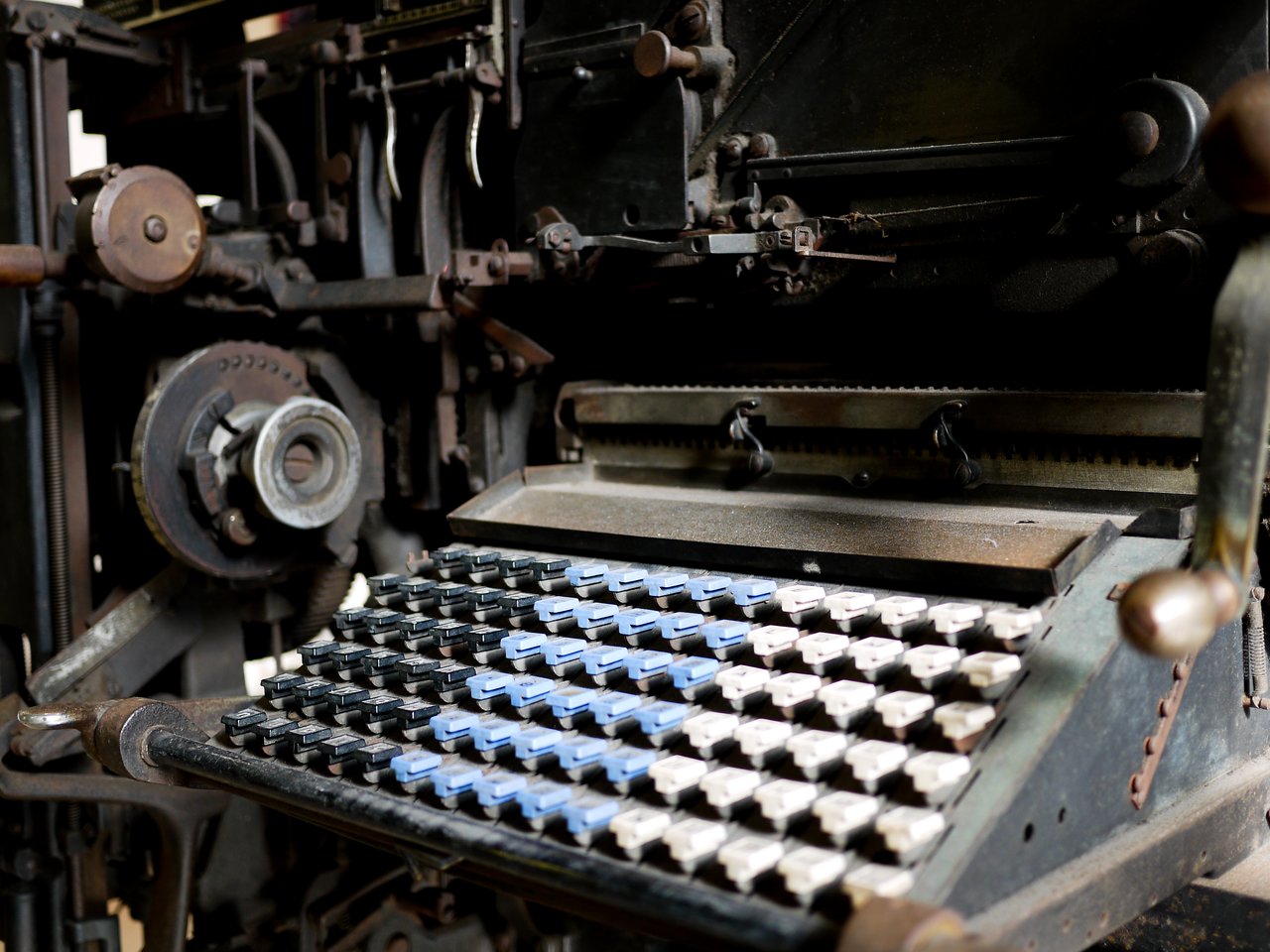 Close-up of an old Linotype machine with a keyboard and mechanical components used for typesetting in printing.