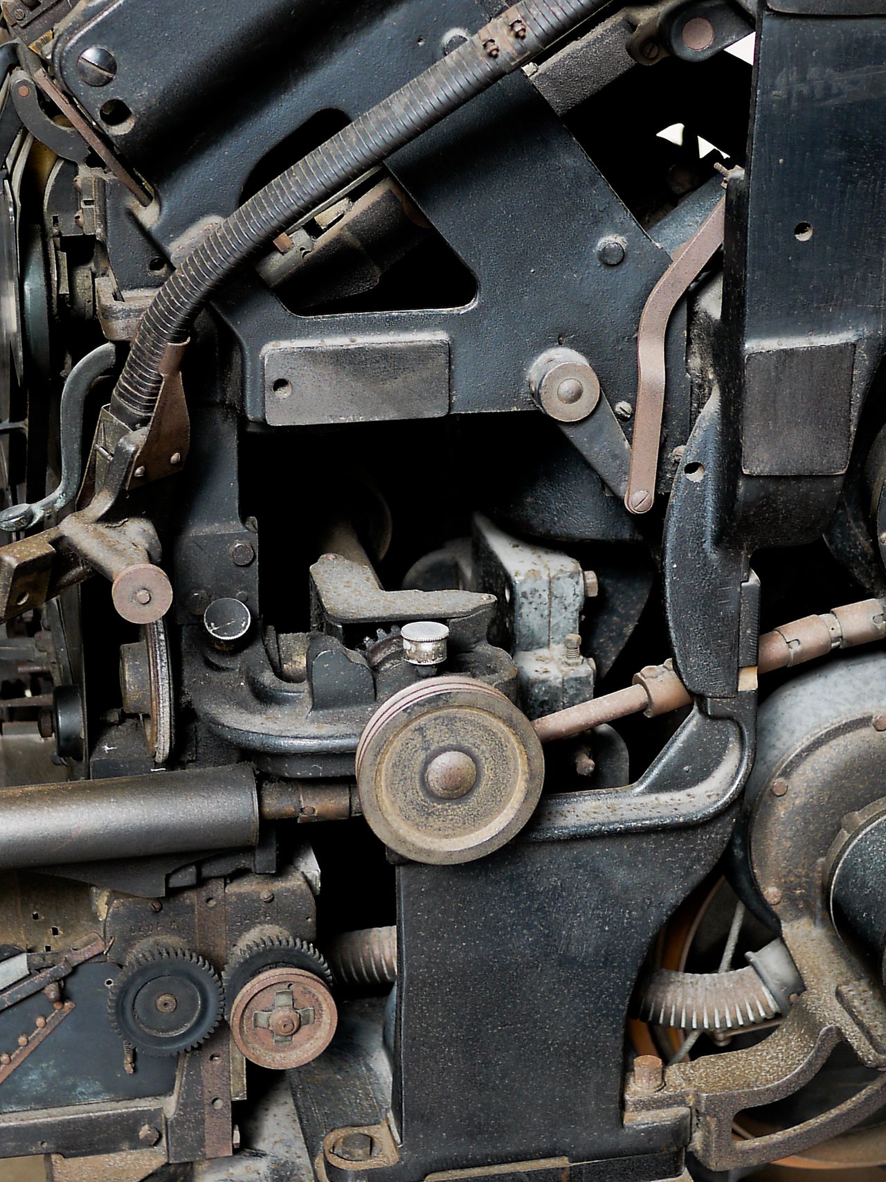 Close-up of an old Linotype machine with gears, levers, and rollers used for typesetting in printing.