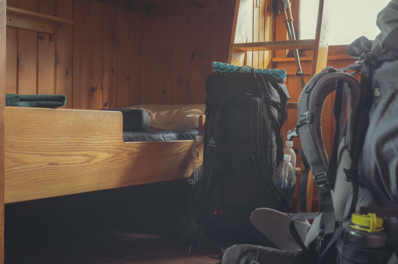 A backpack resting next to a wooden bunk bed.