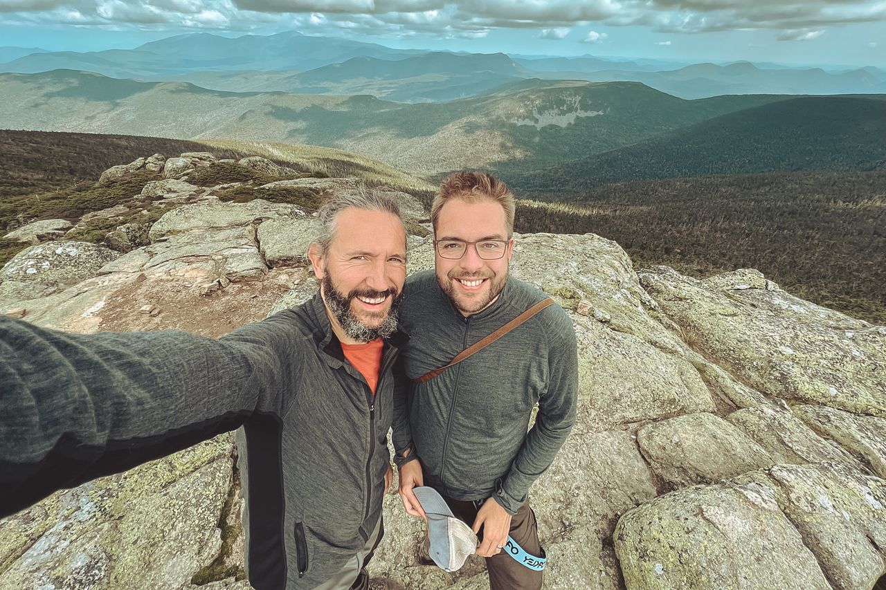 A selfie of two happy hikers on top of a mountain.