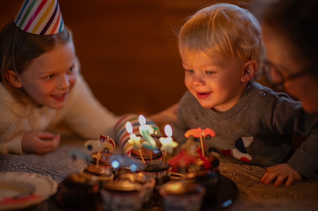 A young child leans over birthday cupcakes ready to blow out the candles.