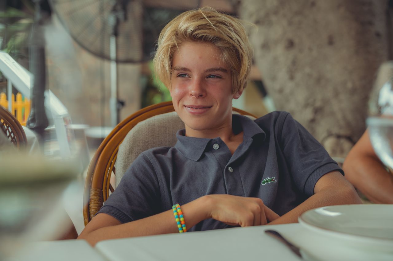 A teenage boy sitting at a restaurant table.