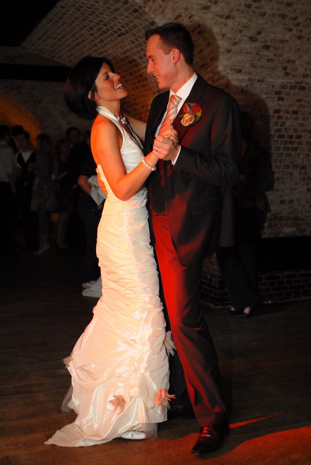 A bride and groom dance together, smiling and looking at each other on their wedding day.