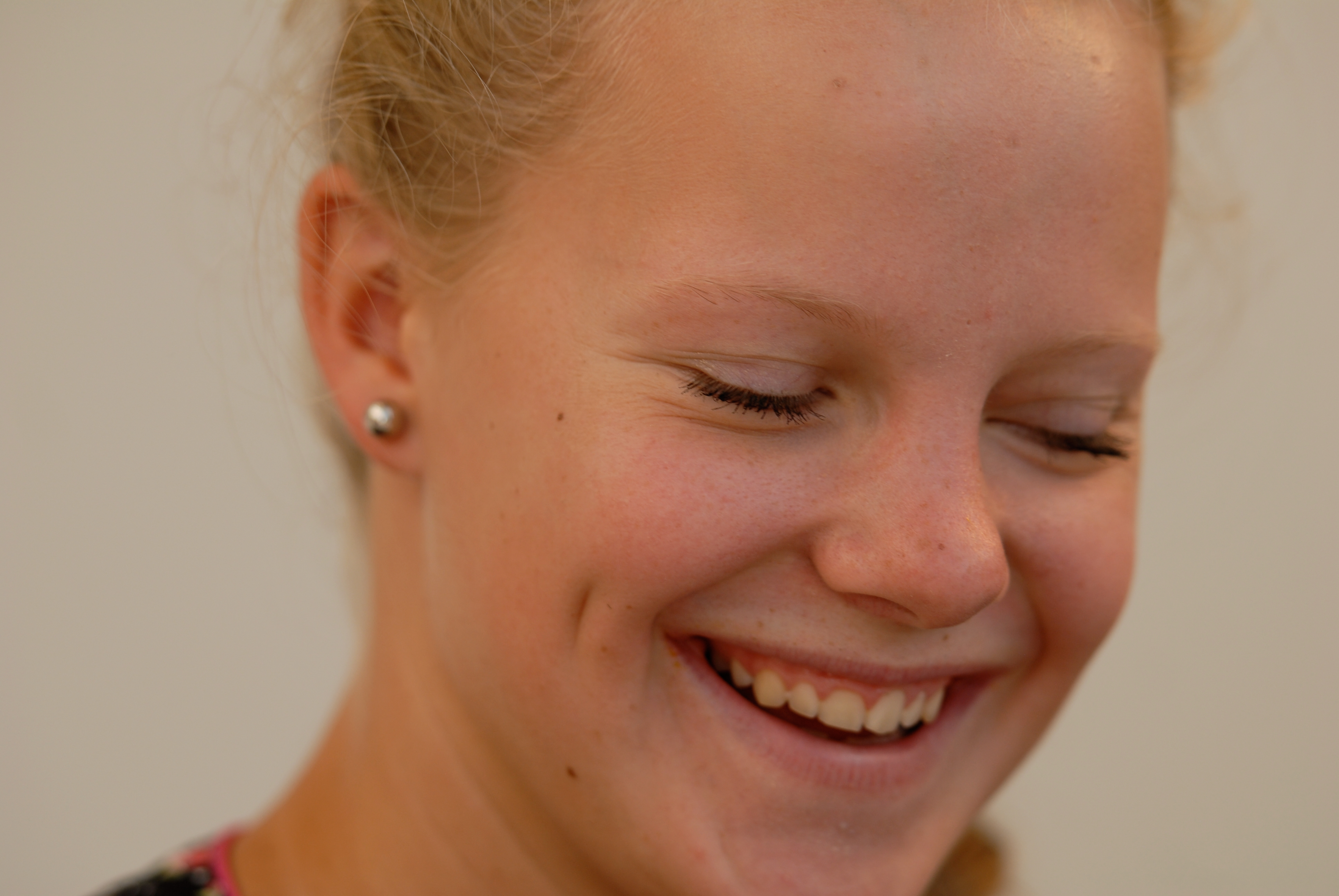 A young woman smiles with her eyes closed, appearing happy at the party.