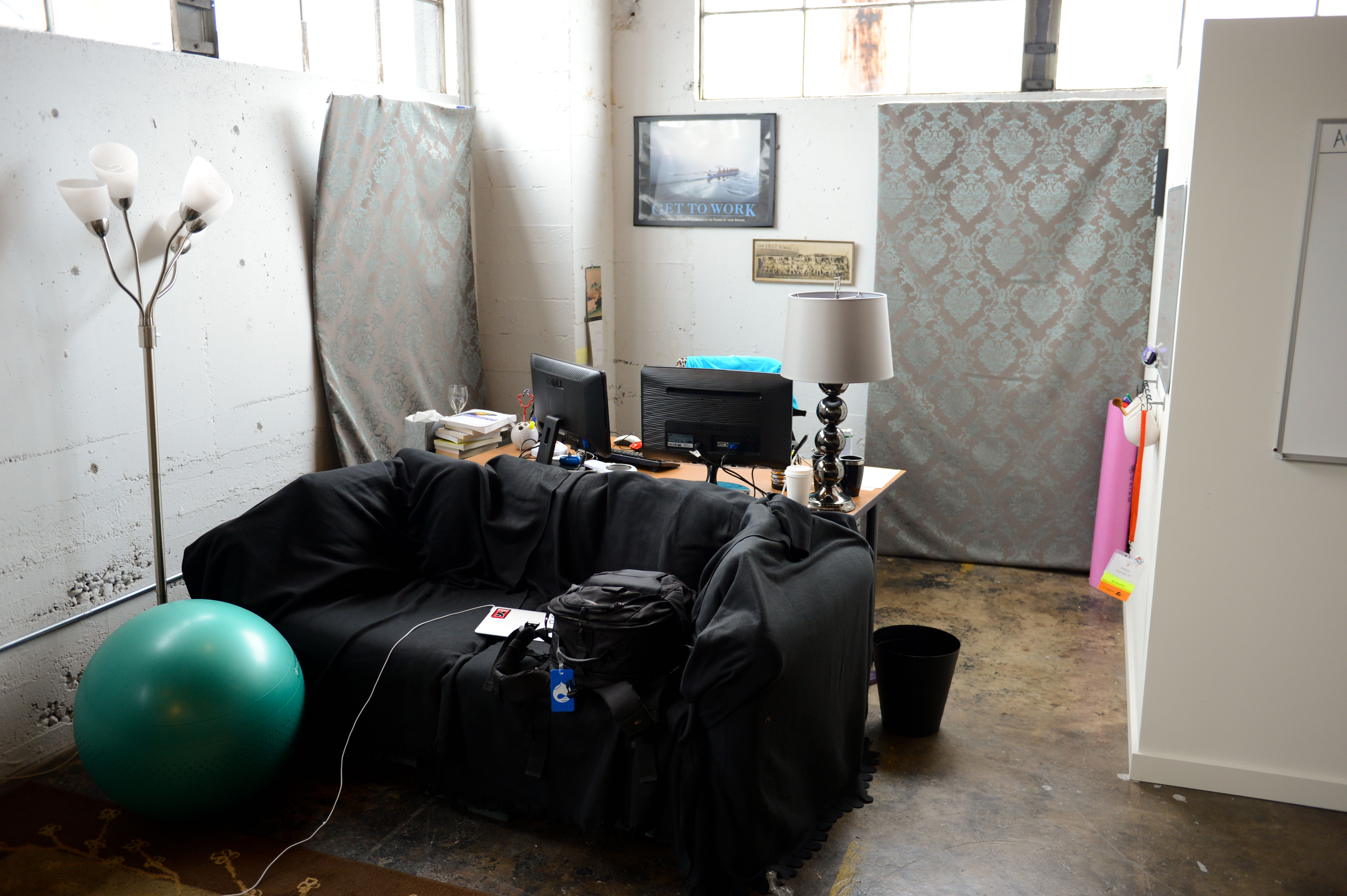 A workspace with a desk, computer, and couch in an industrial-style office with minimal decor.