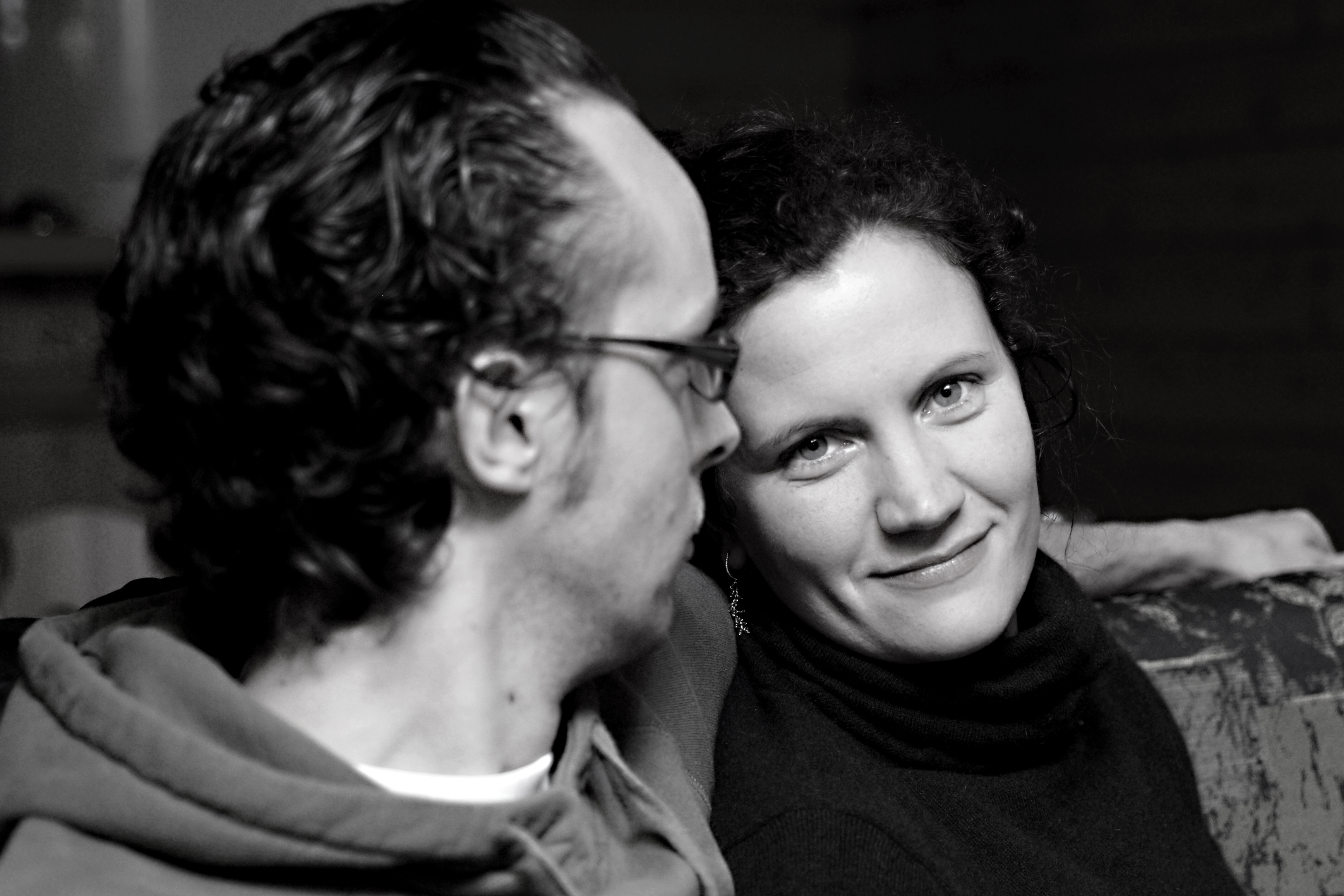 A woman smiles at the camera while a man beside her looks in her direction.