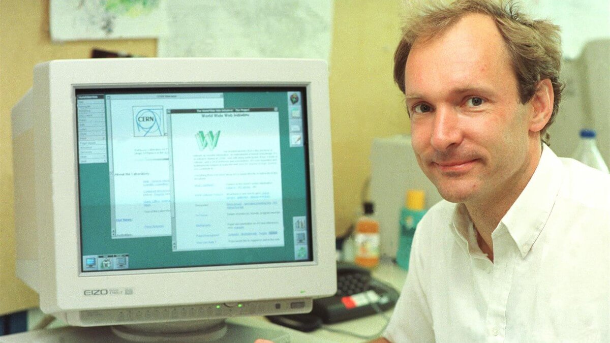 Tim Berners-Lee sitting in front of a computer showing the first website
