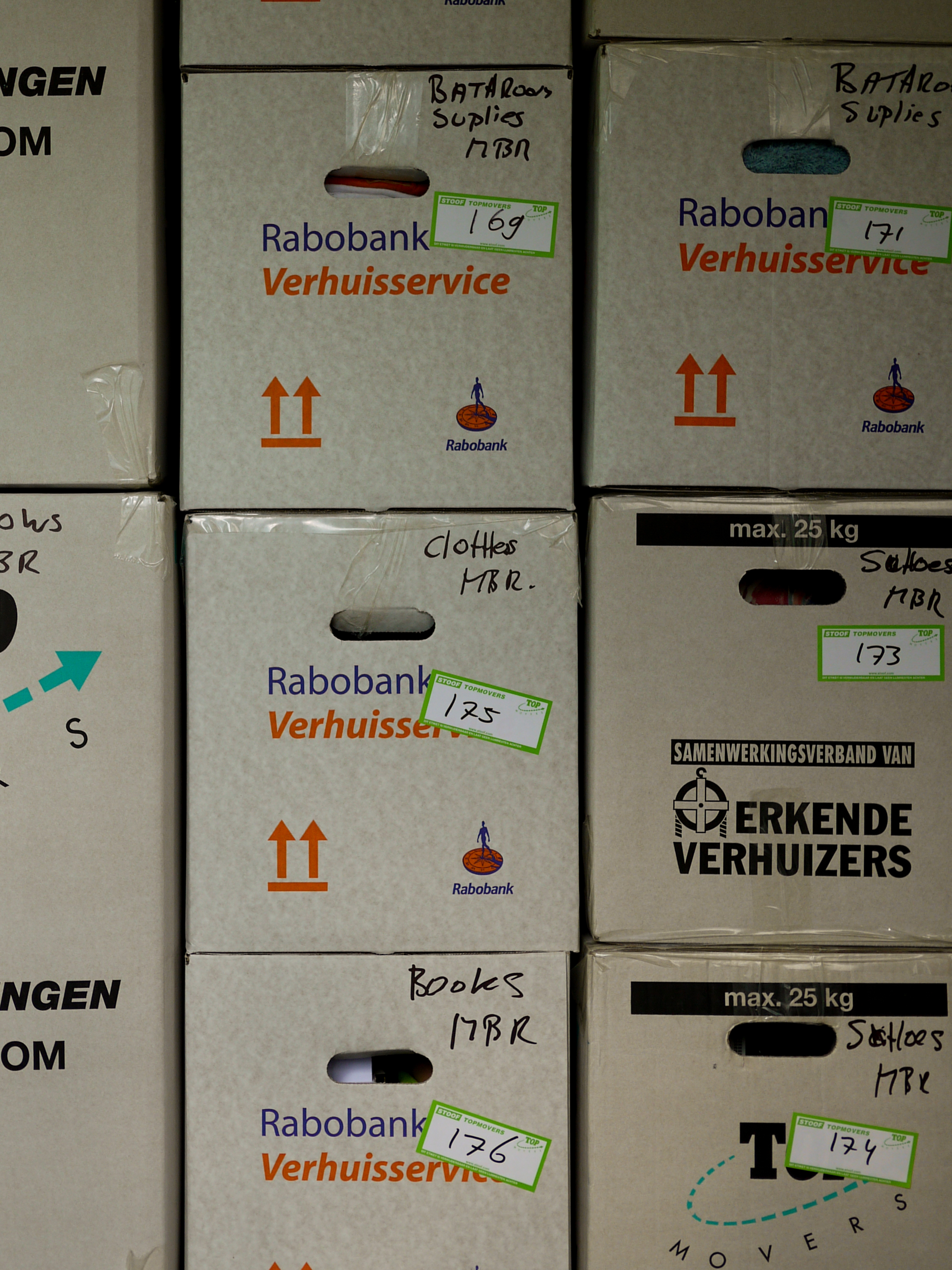 Stacked moving boxes labeled with contents like clothes, books, and bathroom supplies, marked with numbers for organization.