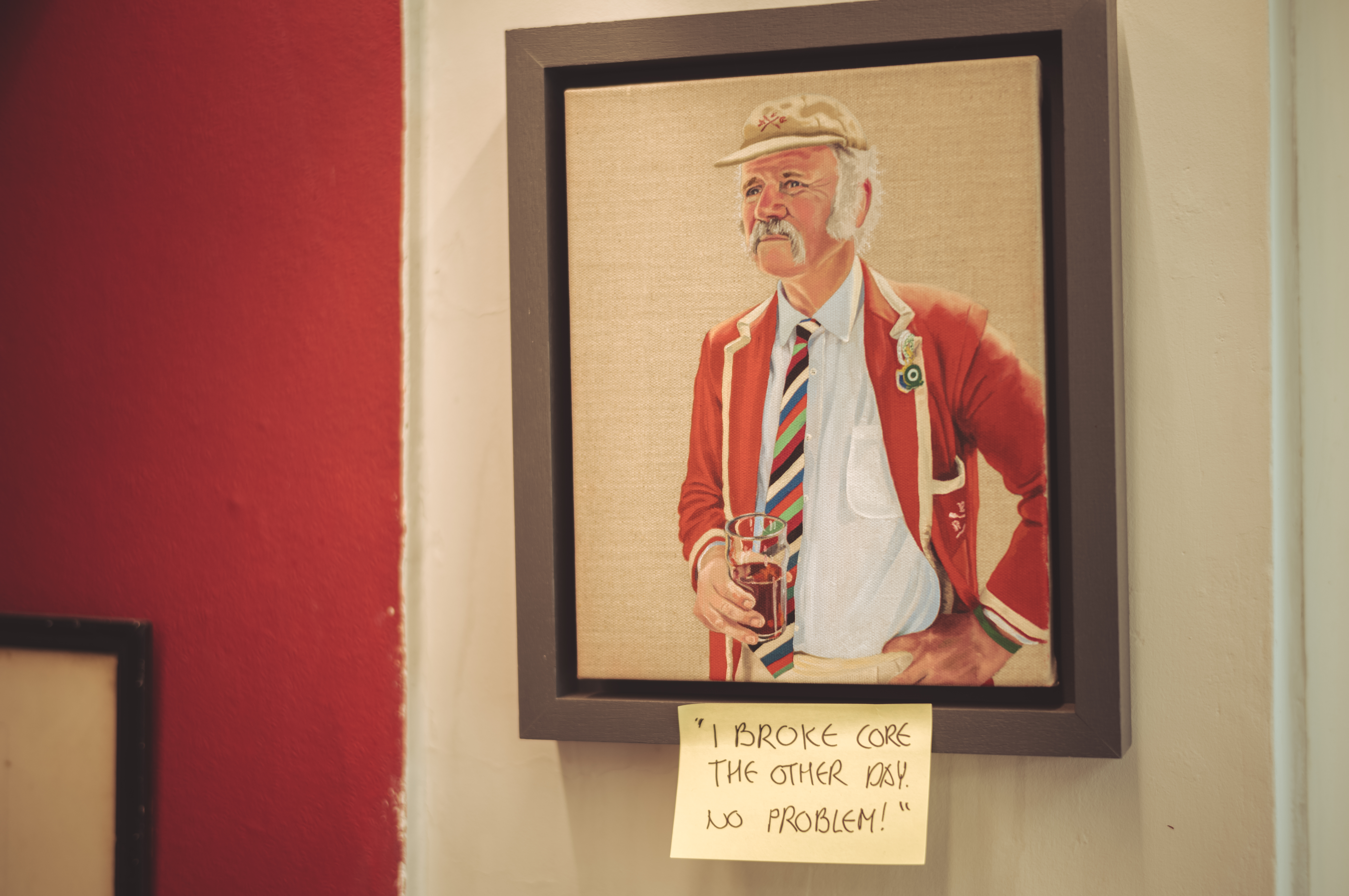 A painting of a man holding a beer. The frame has a sticky note with the text: &quot;I broke core the other day. No problem!&quot;.