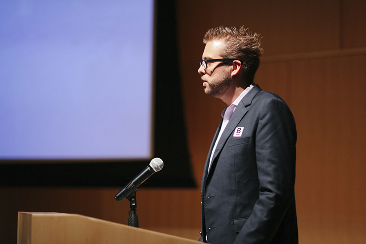 A man in a suit speaks into a microphone at the Boston Gov launch event.