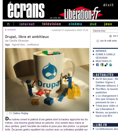 A white mug with the Drupal logo is filled with LEGO bricks, while LEGO figures interact around it.