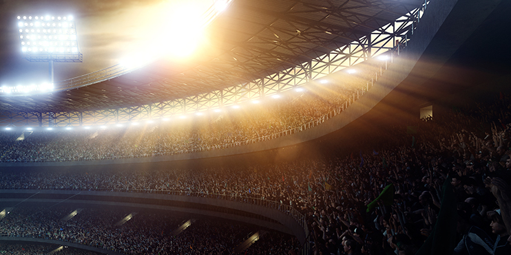 A large stadium filled with cheering fans, bright stadium lights shining over the crowd.